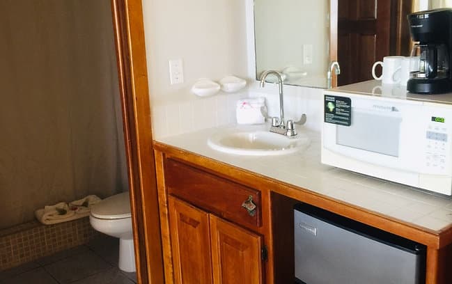 A functional kitchenette area with a sink, microwave, coffee maker, and mini-fridge.