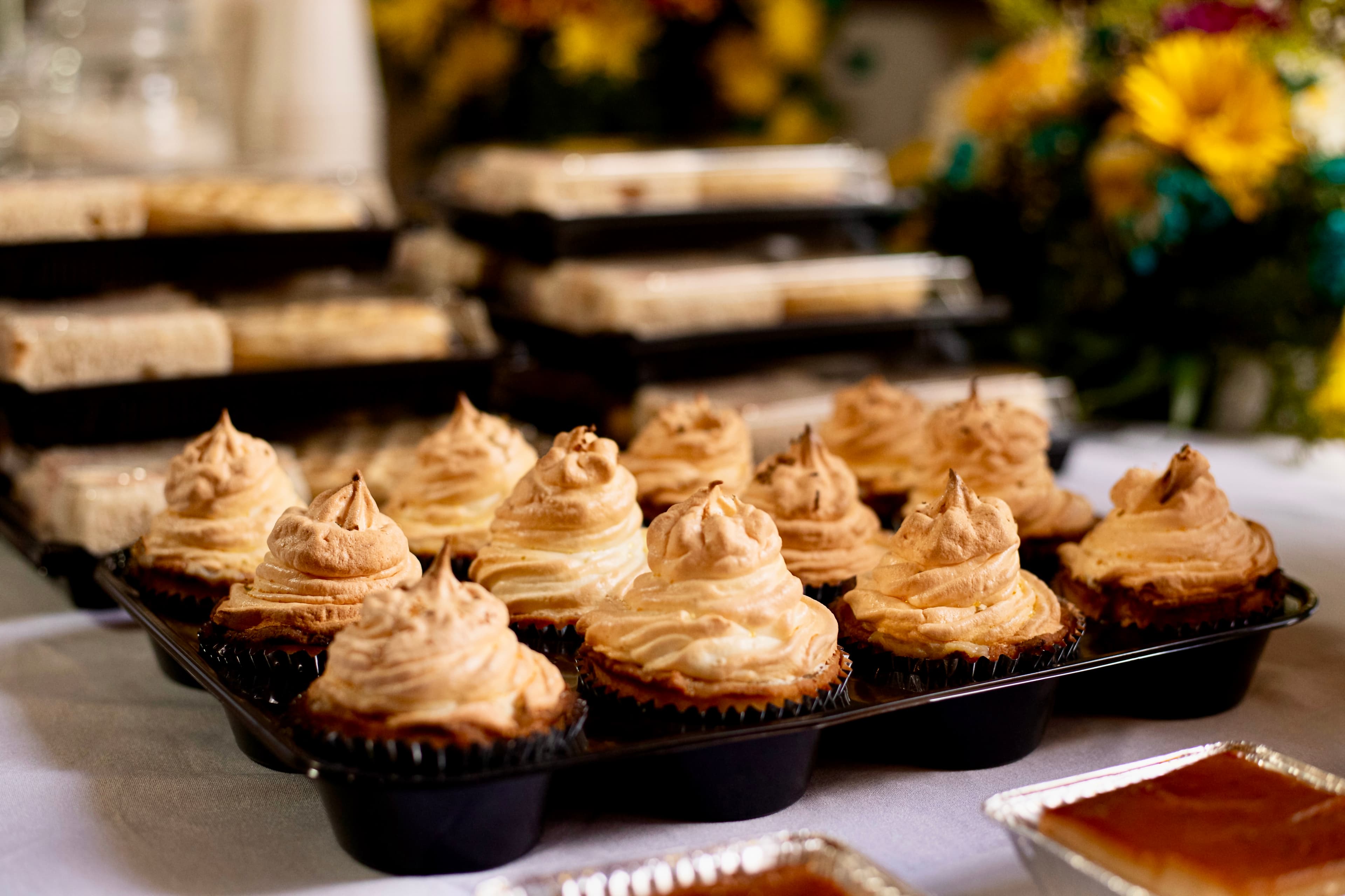 A tray of beautifully decorated cupcakes with swirled meringue frosting.