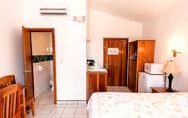 A well-appointed bedroom with a king-size bed, dark gray bedding, nightstands with lamps, and a ceiling fan for comfort.