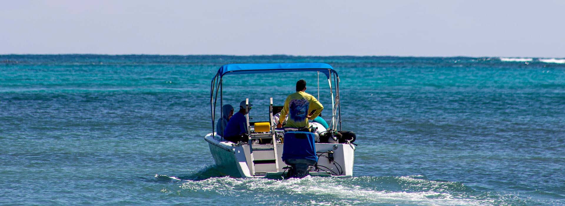 A small boat with passengers navigates through clear blue waters.