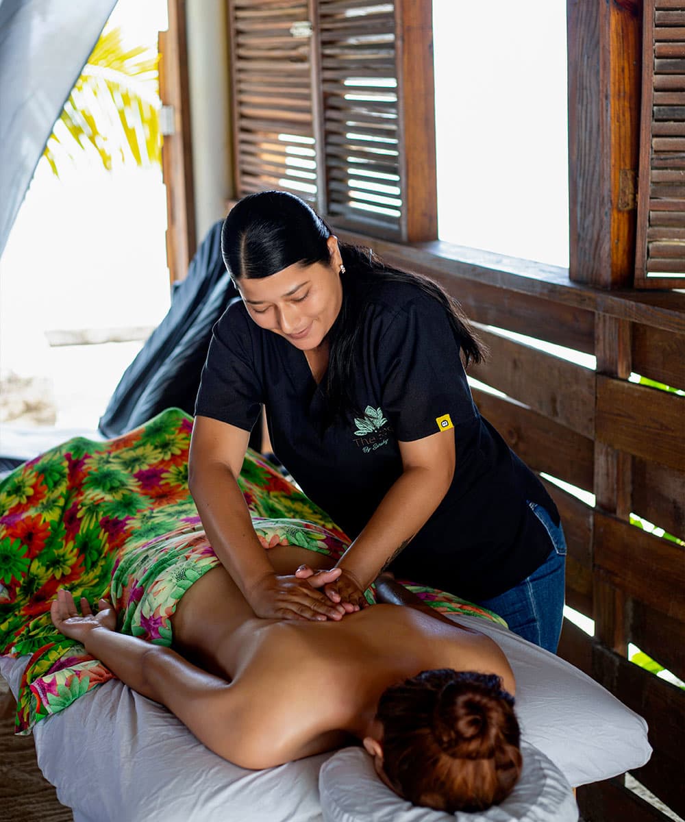 A person receives a massage in a serene, open-air setting.